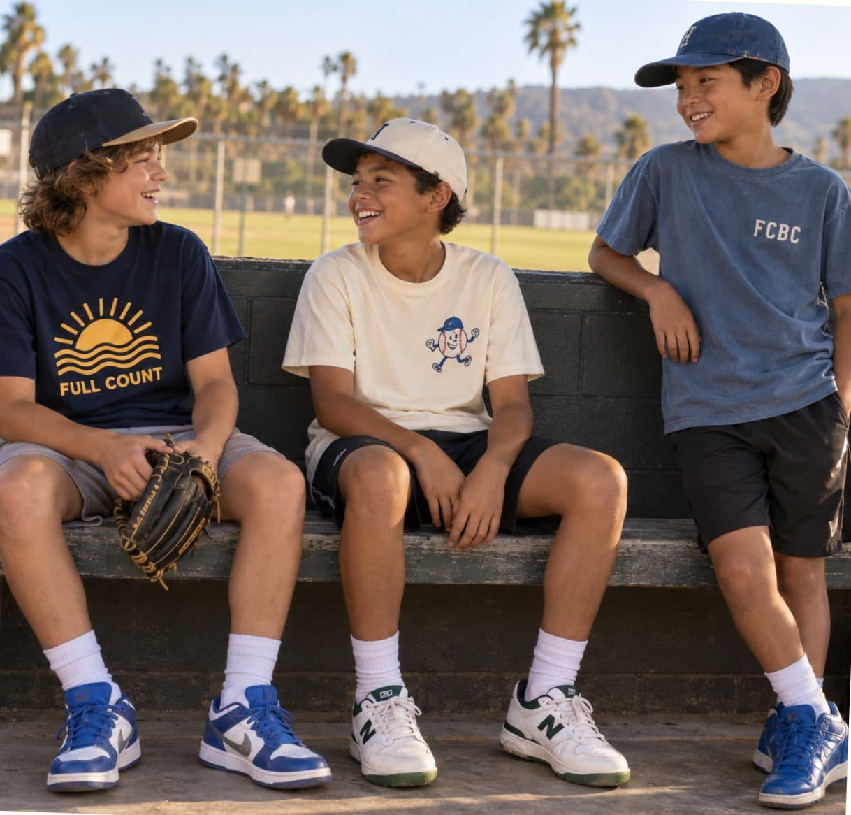 Three kids in FCBC tees laughing on the dugout bench